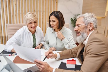 middle aged bearded realtor showing contract to lgbt family in real estate office, lesbian couple clipart