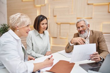 bearded realtor showing contract to lesbian couple in real estate office, middle aged lgbt family clipart