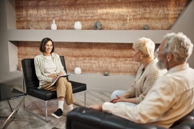 Terapi seansı sırasında orta yaşlı evli bir çiftle konuşan pozitif psikolog.