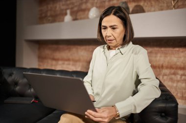 Çok ırklı orta yaşlı psikolog, dizüstü bilgisayar ve online oturum sırasında müşteriyle konuşuyor.