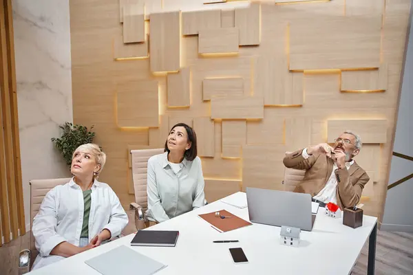 stock image bearded middle aged realtor in glasses showing presentation to lgbt clients in real estate office