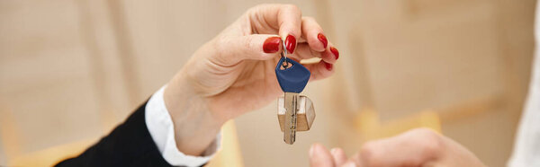 closed up banner of cropped realtor giving key from new house to client in real estate office