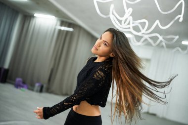 Artistik uzun saçlı Afro-Amerikan dansçı siyah hasat süveteri içinde dans salonunda prova yapıyor.