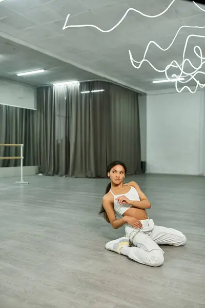 stock image attractive african american woman in white sportswear rehearsing modern dance in spacious studio