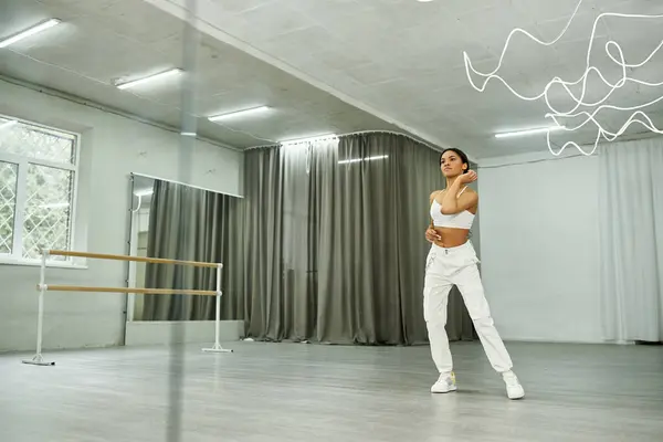 stock image artistic african american dancer in white sportswear rehearsing and training near mirrors in studio