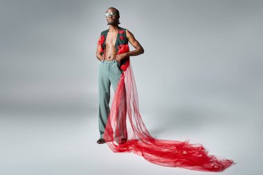 Güneş gözlüklü genç Afrikalı Amerikalı adam. Canlı giyinmiş, kameraya bakıyor. Moda kavramı.