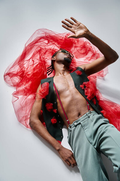 Handsome fashionable african american man with sunglasses in trendy outfit lying on floor, fashion