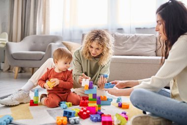 Neşeli lezbiyen çift evde oyuncak bebekleriyle oynuyorlar, aile kavramı.