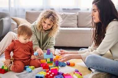 Mutlu lezbiyen çift evde oyuncak bebekleriyle oynuyorlar, aile kavramı.