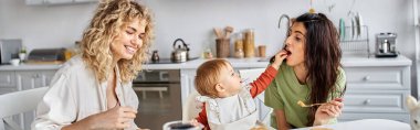 Neşeli Lgbt çifti, küçük kızlarıyla, aile kavramlarıyla, afişleriyle lezzetli bir kahvaltı yapıyorlar.