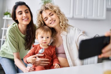 Igbt çifti, kızlarıyla birlikte mutfaktaki selfie çekiyorlar. Aile kavramı.
