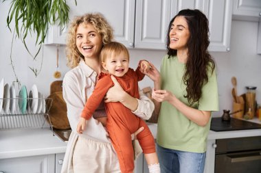 Sevimli, neşeli Igbt çifti küçük kızlarıyla mutfakta oynuyorlar, aile kavramı.