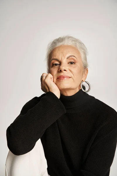 stock image portrait of dreamy middle aged business woman in elegant smart casual attire on grey background