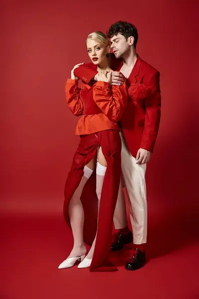 Knappe Man Omarmen Blonde Vrouw Elegante Kleding Rode Achtergrond Modieus — Stockfoto