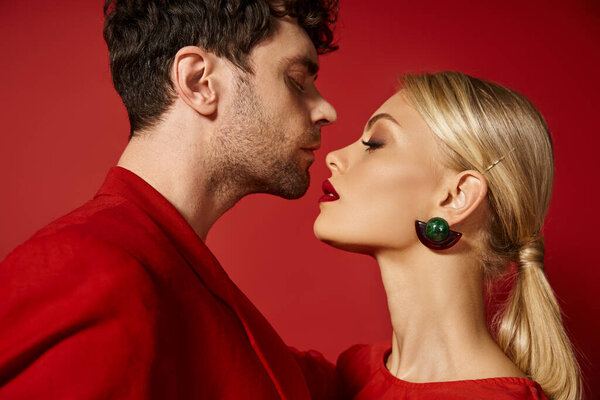 side view of handsome man posing with attractive blonde woman with red lips on vibrant background