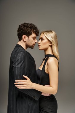 Kırmızı tasarımcı kılığındaki yakışıklı adam canlı arka planda sarışın mankenle poz veriyor. Moda bir çift.