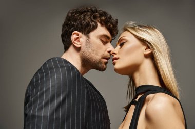 Kırmızı tasarımcı kılığındaki yakışıklı adam canlı arka planda sarışın mankenle poz veriyor. Moda bir çift.