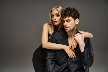 Kırmızı tasarımcı kılığındaki yakışıklı adam canlı arka planda sarışın mankenle poz veriyor. Moda bir çift.