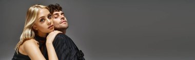 Kırmızı tasarımcı kılığındaki yakışıklı adam canlı arka planda sarışın mankenle poz veriyor. Moda bir çift.