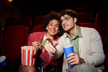 Canlı giysiler içinde neşeli ırklar arası bir çift sinemada, sevgililer gününde eğleniyor.