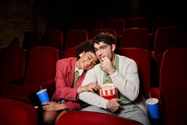 Gözlüklü yakışıklı adam buluşmada Afrikalı Amerikalı kız arkadaşının yanında patlamış mısır yiyor.