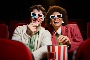 Eski 3 boyutlu gözlüklü neşeli çok ırklı çift sevgililer gününde sinemada film izliyor.