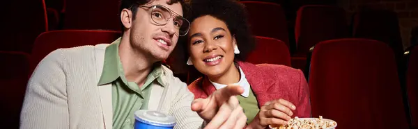 stock image jolly interracial couple in vibrant attires enjoying movie at cinema on date, Valentines day, banner