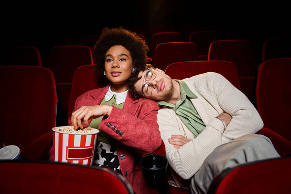 handsome man enjoying date at cinema with his african american girlfriend with head on her shoulder