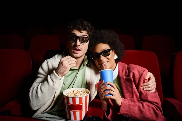 Üç boyutlu gözlüklü neşeli çok kültürlü çift sevgililer gününde sinemada film izliyorlar.