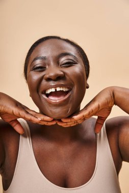 Mutlu artı boyut Afrikalı Amerikalı kadın. Yüzüne yakın ellerle arka planda eşleşme var.
