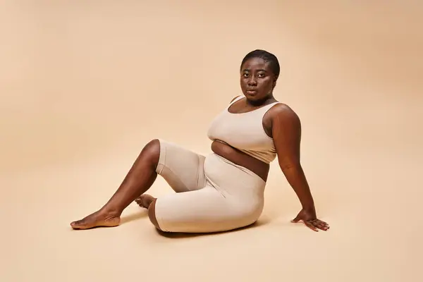 加尺寸非洲裔美国年轻女子 穿着米色内裤 在匹配的背景下摆姿势 — 图库照片