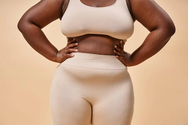 stock image cropped plus size woman in underwear posing on beige backdrop, body positive and female empowerment