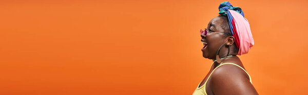 Banner of plus size african american woman in headscarf and trendy sunglasses on orange backdrop