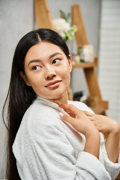 stock image portrait of young asian with acne-prone skin standing in modern bathroom and looking away