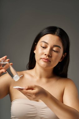 young asian woman with brunette hair and acne prone skin looking at mirror in bathroom, banner clipart