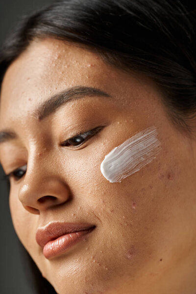 young asian woman with brunette hair and acne prone skin looking at mirror in bathroom, banner