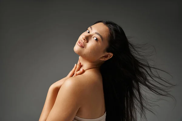 stock image young asian woman with brunette hair and acne prone skin looking at mirror in bathroom, banner