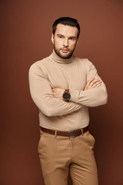 Kararlı ve yakışıklı balıkçı yakalı adam çapraz kollar ve keskin bakışlarla poz veriyor.