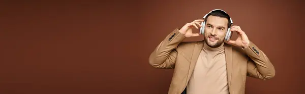Zarif Giyinmiş Karizmatik Bir Adam Bej Afiş Üzerine Kablosuz Kulaklıklarıyla — Stok fotoğraf