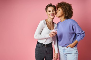 Neşeli lezbiyen kadın, Valentins Günü 'nde Afrikalı Amerikalı kız arkadaşının hediyesini ve elini tutuyor.