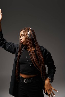 20 'li yaşlarındaki Afrikalı Amerikalı kız gri kulaklıkla müzik dinlerken dans ediyor.