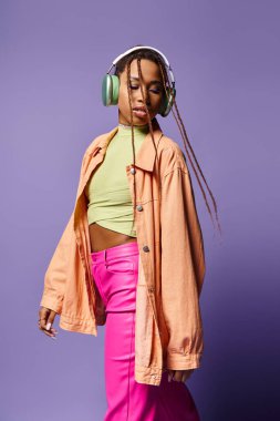 20 'li yaşlardaki Afro-Amerikan kadınları kablosuz kulaklıklarla müzik dinliyor ve mor renkte yürüyorlar.