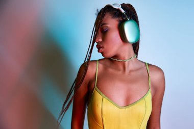 young african american woman with dreadlocks in wireless headphones enjoying music on blue clipart