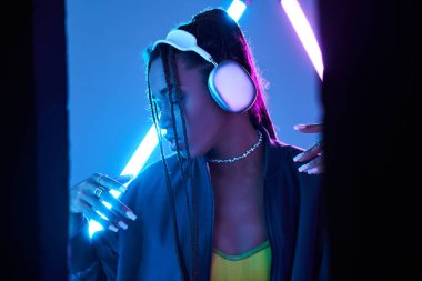 Güzel Afro-Amerikan kadın kulaklıklı stüdyoda müzik dinliyor mavi floresan ışığıyla