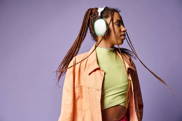 紫色の背景にヘッドフォンと活気に満ちた服装で喜ぶアフリカ系アメリカ人の少女の静かなダンス — ストック写真