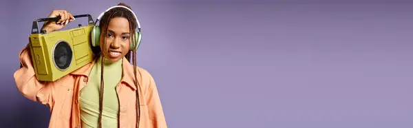 紫色のレトロブームボックスと立っているワイヤレスヘッドフォンの幸せなアフリカ系アメリカ人女性 バナー — ストック写真