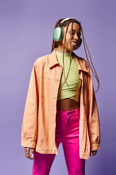 20代のアフリカ系アメリカ人の少女がリズムに移行するワイヤレスヘッドフォンで音楽を聴きながら微笑んだ — ストック写真