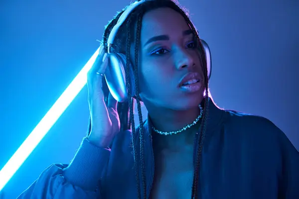 stock image beautiful african american woman in headphones enjoying music in studio with fluorescent light