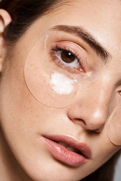 A young Caucasian woman with under eye patches exuding a serene beauty routine, close up