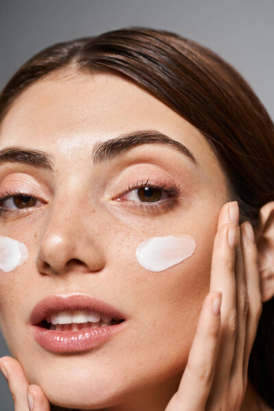 Молодая белая женщина с брюнетками, наслаждающаяся роскошным уходом за кожей, с толстым слоем крема на лице.